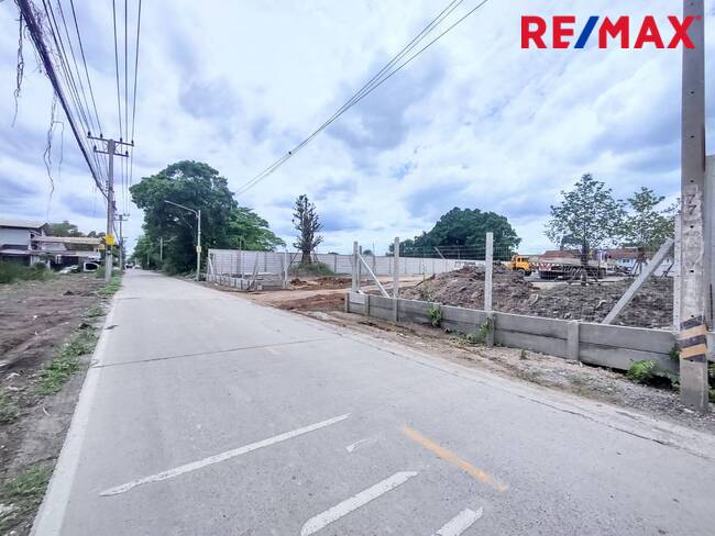 For SaleLandPathum Thani,Rangsit, Thammasat : Land for sale, Rangsit Khlong Sam Soi 2/1, area 2 rai, pink city plan. The plot is rectangular, filled in higher than the road and surrounded by a concrete fence.